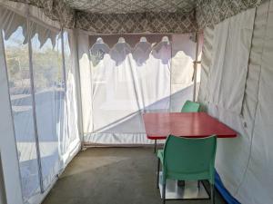 a tent with a red table and two green chairs at Kutch Leela Resort in Mandvi