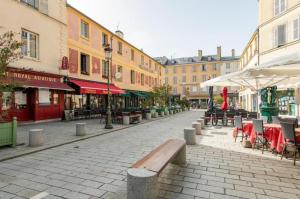 une rue de la ville avec des tables, des chaises et des bâtiments dans l'établissement Géranimus Versailles: Notre-Dame, à Versailles