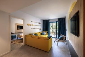 a living room with a yellow couch and a bedroom at Krk Sunny Hotel in Krk