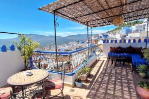a balcony with tables and chairs and a view of a city at Dar Fezna - top location, stunning 360 views in Chefchaouen