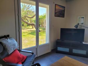 a living room with a tv and a window at DUNES - Villa Patio Avec Jardin - proche Plage de la Gravière in Soorts-Hossegor