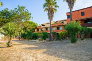 een oranje gebouw met palmbomen ervoor bij Lagrange Vacances Résidence du Golf in Saint-Cyprien