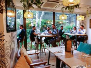 un gruppo di persone seduti ai tavoli in un ristorante di Novotel Paris La Defense Esplanade a Courbevoie
