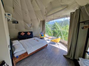 a bedroom with a bed and a large window at Glamping Georgia Krikhi in Ambrolauri