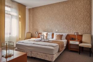 a hotel room with a bed and a chair at Boutique Hotel Sopianae in Pécs