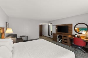 a hotel room with a bed and a desk with a television at Hampton Inn Bridgeport/Clarksburg in Bridgeport