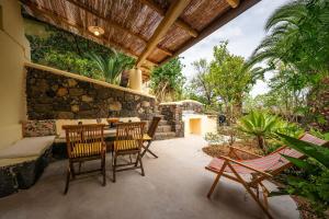 a patio with a table and chairs and a stone wall at Casa Scirocco Lipari in Lipari
