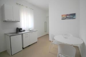 a white kitchen with a table and white chairs at Nefeli's Apartment in Himare