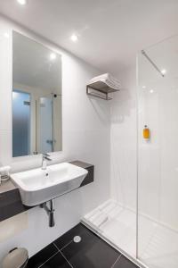 a white bathroom with a sink and a shower at AP Eva Senses in Faro