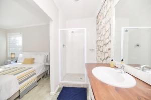 a white bathroom with a sink and a bed at Seafever in Arniston in Arniston +45 photos