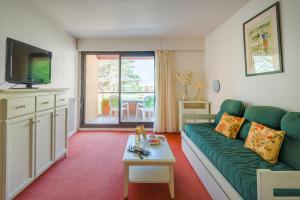 een woonkamer met een groene bank en een tv bij Lagrange Vacances Résidence du Golf in Saint-Cyprien