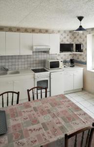 VergezacにあるMaison de 2 chambres avec terrasse amenagee a Vergezacのキッチン(白いキャビネット、テーブル、椅子付)