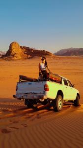 wadi rum camp stars & jeep tour في وادي رم: امرأة جالسة في الجزء الخلفي من شاحنة في الصحراء