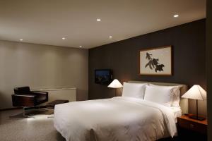 a bedroom with a large white bed and a chair at Oriens Hotel & Residences Myeongdong in Seoul +90 photos