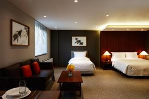 um quarto de hotel com duas camas e um sofá em Oriens Hotel & Residences Myeongdong em Seul