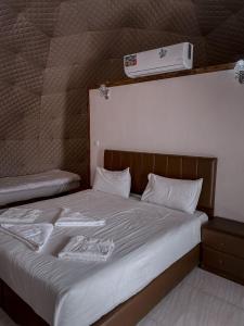 wadi rum camp stars & jeep tour في وادي رم: غرفة نوم بسرير ذو شراشف بيضاء و فاتح للشهية