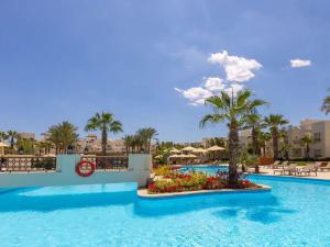 una piscina en un complejo con palmeras en Swissôtel Sharm El Sheikh All Inclusive Collection, en Sharm El Sheikh