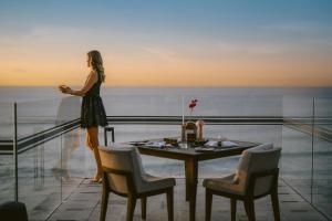 a woman standing on a balcony looking out at the ocean at Jumeirah Bali in Uluwatu