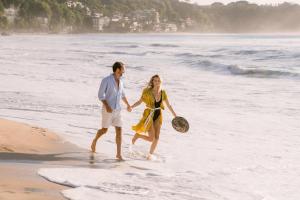 a man and a woman walking on the beach at Jumeirah Bali in Uluwatu