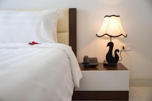 a bed with a lamp and a phone on a night stand at Noi Bai Airport Hotel in Noi Bai