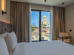 a hotel room with a large bed and a large window at Novotel Tbilisi Center in Tbilisi City