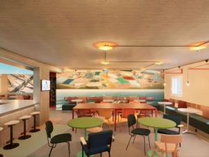 ニースにあるGreet Hotel Nice Aéroport Promenade des Anglaisのテーブルと椅子、壁画のあるレストラン