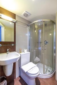 a bathroom with a shower and a toilet and a sink at Coronation Hotel in London