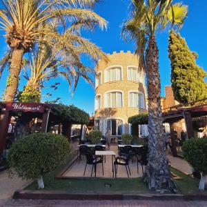a building with tables and palm trees in front of it at Casa Rosalia in Orihuela Costa
