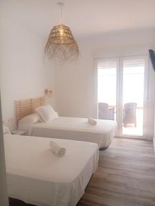 um quarto com 3 camas e um lustre em HOSTAL CASA EMILIO em Almería