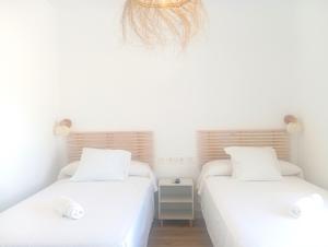 2 camas individuais num quarto com paredes brancas em HOSTAL CASA EMILIO em Almería