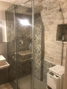 een glazen douche in een badkamer met een stenen muur bij Pignarè in Locorotondo