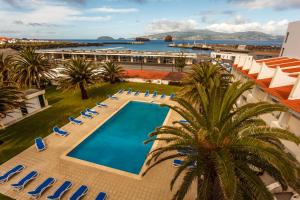 een uitzicht over het zwembad van het resort met stoelen en een palmboom bij Hotel Caravelas in Madalena