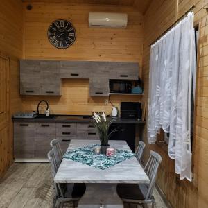 a kitchen with a table and a clock on the wall at MARWIKOWE Domki Wypoczynkowe in Sieraków