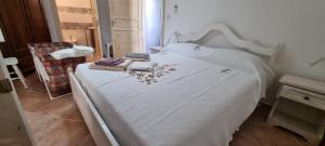 a bedroom with a white bed with some leaves on it at La Casetta Al Mar in Porto Cesareo