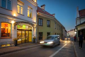 ein Auto, das eine Stadtstraße mit Gebäuden entlangfährt in der Unterkunft City Hotels Rūdninkai in Vilnius
