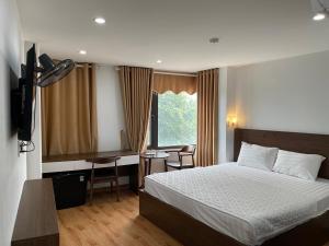 a bedroom with a bed and a desk and a window at Noi Bai Airport Hotel in Noi Bai