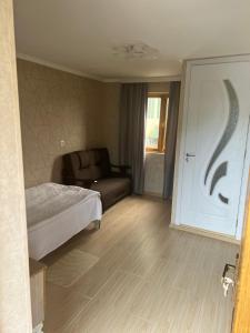 a bedroom with a bed and a couch next to a door at Hotel-Restaurant Khvanchkara in Khvanchkara