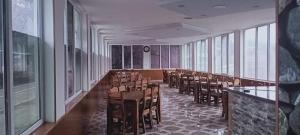 a dining room with chairs and tables and windows at Hotel-Restaurant Khvanchkara in Khvanchkara