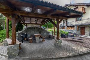 a patio with a stone fireplace and a wooden pergola at Wellness Vila Limaco Slovakia in Horné Jaseno