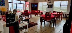 a dining room with red tables and chairs and windows at Casa Do Mar Guest House in Praia do Tofo