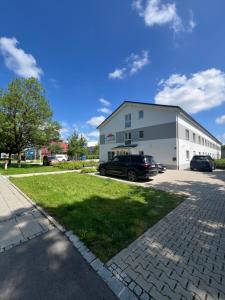 a large white building with cars parked in a parking lot at Boardinghouse MDS in Aschheim