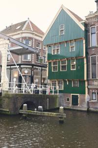 un bâtiment vert à côté d'une rivière avec des bâtiments dans l'établissement Huis met de Kogel, à Alkmaar