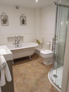 a bathroom with a tub and a toilet and a sink at The Kings Head in Whiteparish