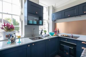 Una cocina con gabinetes azules y un fregadero. en Dream Stays Bath - Kingsmead Street, en Bath