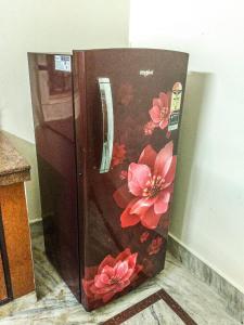 Elle comprend un réfrigérateur en bois orné de fleurs. dans l'établissement Serene Stays at Varanasi - 5BHK Luxirious villa, à Varanasi