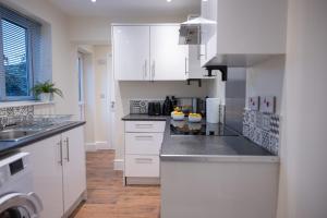 a kitchen with white cabinets and a counter top at The Orange County in Stoke on Trent +19 photos