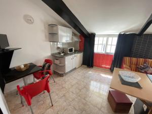 a kitchen and dining room with red chairs and a table at Apartamentos Blanco Y Negro in A Guarda