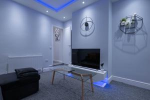 a living room with a tv and a couch and a table at The Orange County in Stoke on Trent