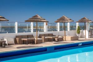 a pool with chairs and umbrellas next to a pool at AP Eva Senses in Faro