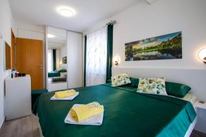 a bedroom with a green bed with two towels at Apartments Mateo in Rovinjsko Selo